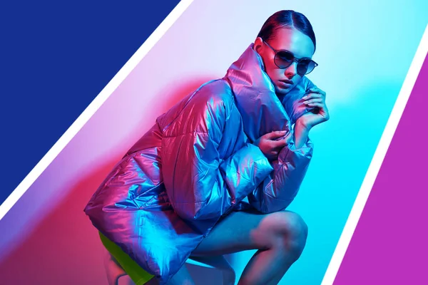 Güneş gözlüklü zarif bir kadının moda portresi. Gümüş rengi ceketli, neon ışıklı