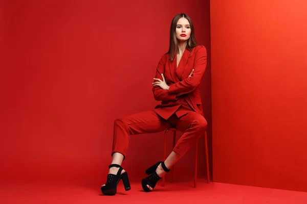 Fashion young woman in red suit. Red background.