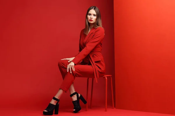 Fashion young woman in red suit. Red background.