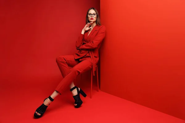 赤いスーツのファッションの若い女性 赤の背景 — ストック写真