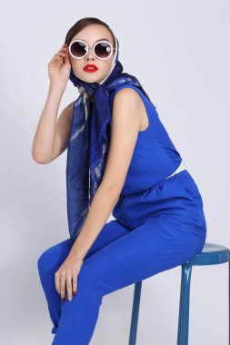 Geçmişe dönük genç bir kadın. Güneş gözlüğü ve ipek eşarp, mavi tulum. 60 'ların moda retro kadını. 