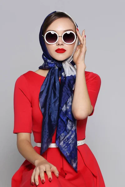 Young woman in retro style. Sunglasses and silk scarf. Sixties style fashion retro woman.