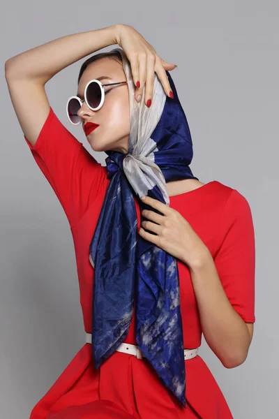 Young woman in retro style. Sunglasses and silk scarf. Sixties style fashion retro woman.