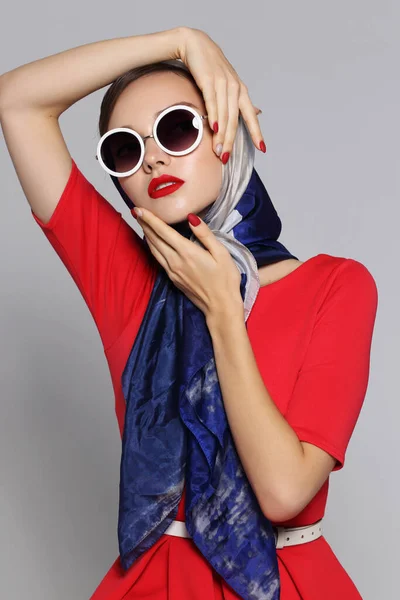 Young woman in retro style. Sunglasses and silk scarf. Sixties style fashion retro woman.