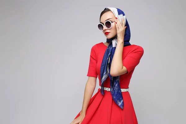 Young woman in retro style. Sunglasses and silk scarf. Sixties style fashion retro woman.