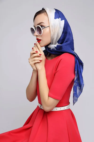 Young woman in retro style. Sunglasses and silk scarf. Sixties style fashion retro woman.