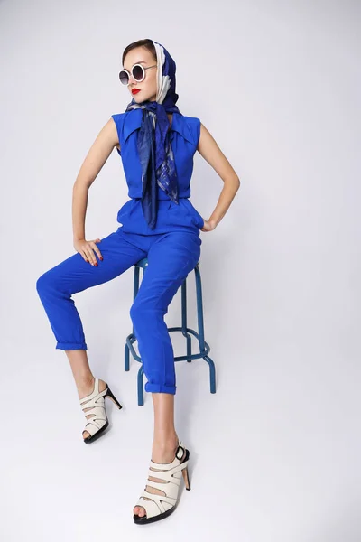Young woman in retro style. Sunglasses and silk scarf, blue overalls. Sixties style fashion retro woman.