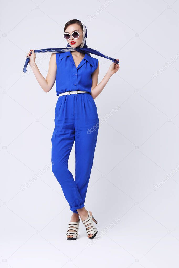 Young woman in retro style. Sunglasses and silk scarf, blue overalls. Sixties style fashion retro woman. 