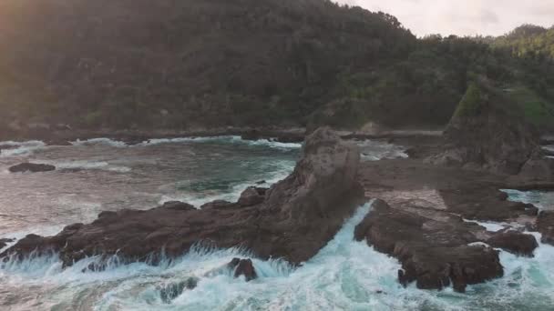 岩のビーチに海の波が飛び散るの映像空撮 ドローンの飛行点から撮影した興味深いショット技術 — ストック動画