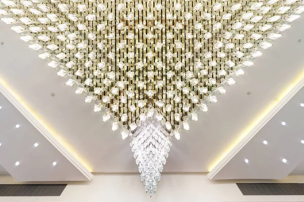 rhythmic texture on suspended ceiling with rows of halogen spots lamps and drywall construction with chandelier. Stretch ceiling white and complex shape.
