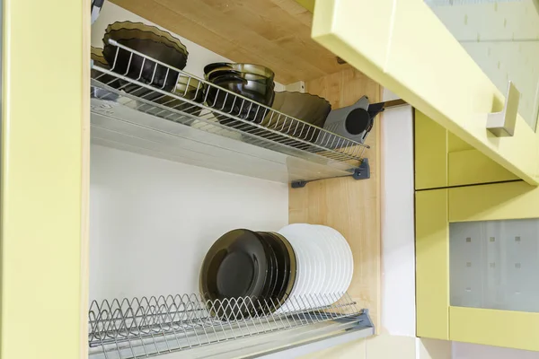 set of plates, cups on the shelf in the kitchen cabinet