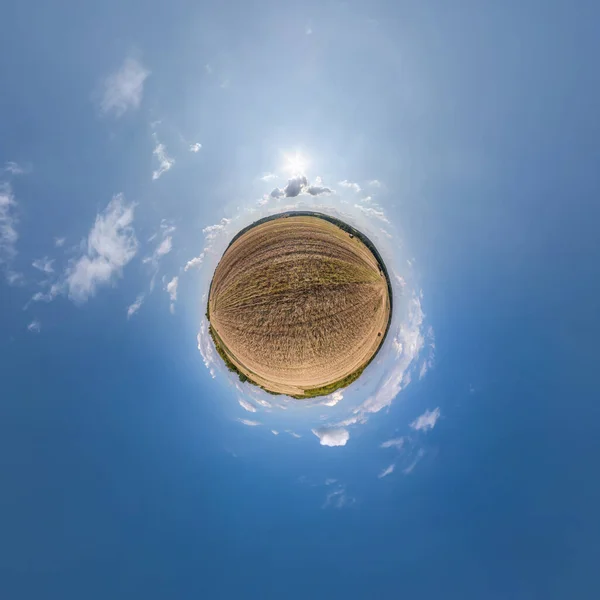 tiny planet in blue sky with sun and beautiful clouds. Transformation of spherical panorama 360 degrees. Spherical abstract aerial view. Curvature of space.