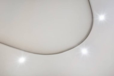 Karmaşık kartonpiyerli tavan ayrıntıları. Apartmanda ya da evde boş bir odada asılmış tavan ve alçıpan inşaatı. Gergin tavan beyaz ve karmaşık şekil.