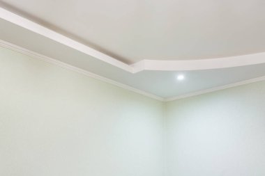 Karmaşık kartonpiyerli tavan ayrıntıları. Apartmanda ya da evde boş bir odada asılmış tavan ve alçıpan inşaatı. Gergin tavan beyaz ve karmaşık şekil.
