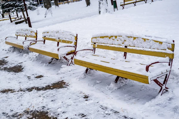 被雪覆盖的黄色木制公园长椅 — 图库照片