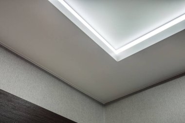 Halojen lambalı asma tavan ve boş bir oda ya da evde alçıpan inşaatı. Gergin tavan beyaz ve karmaşık şekil.