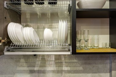 Mutfak dolabındaki rafta tabak, bardak ve şarap bardakları var.