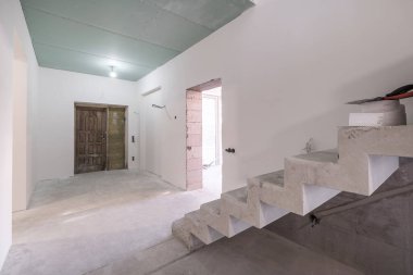 Tamiri ve mobilyası olmayan beton merdivenli boş beyaz oda.