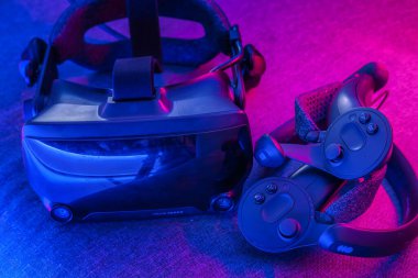 GRODNO, BELARUS - Mart 2021: VR AR 360 sanal gerçeklik gözlüğü kulaklık, neon mavi menekşe arkaplan üzerinde. 3 boyutlu uzayda seyahat ve eğlence için film izleme aygıtı.
