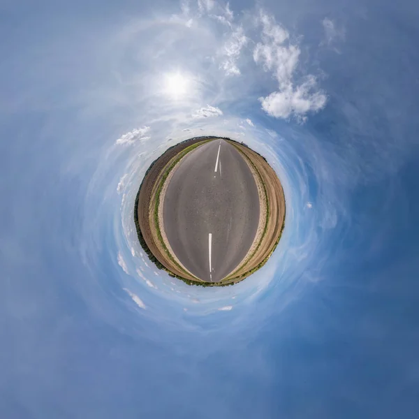green tiny planet in blue sky with sun and beautiful clouds. Transformation of spherical panorama 360 degrees. Spherical abstract aerial view. Curvature of space.