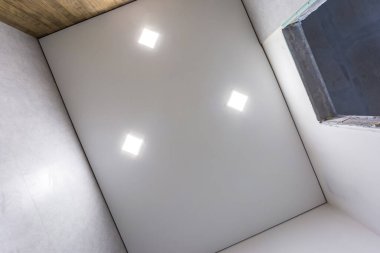 Halojen lambalı asma tavan ve boş bir oda ya da evde alçıpan inşaatı. Gergin tavan beyaz ve karmaşık şekil.