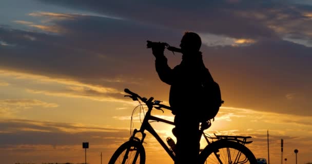 男摄影师的相貌轮廓 骑着相机站在路上 遥望远方 在深红色的夕阳下欣赏美丽的风景 — 图库视频影像