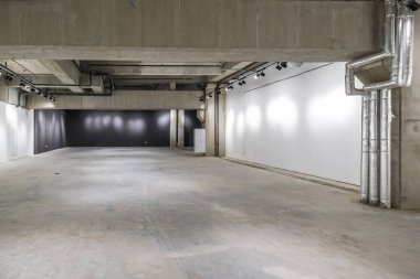 Büyük beton odanın içi depo ya da spot ışıkları olan bir hangar gibi boş.