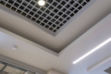 Halojen benekli lambalar ve boş oda veya evde alçıpan inşaatı olan asılmış ve ızgara tavanı. Gergin tavan beyaz ve karmaşık şekil.