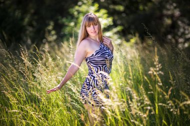 Güzel kız ormanın çalılıklarında duruyor.