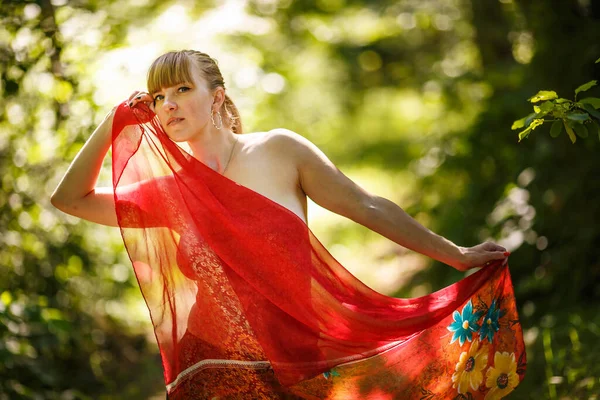 赤いスカーフの美しい少女が森の中に立っています — ストック写真
