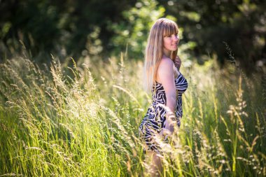 Güzel kız ormanın çalılıklarında duruyor.