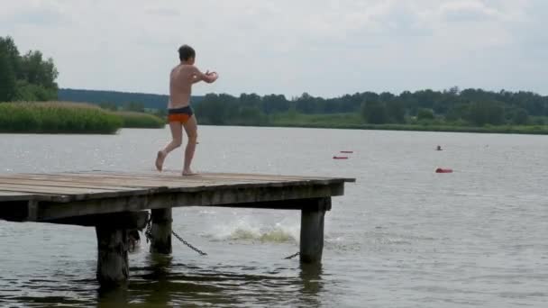 Мальчик Прыгает Воду Озера Возле Деревянного Пирса Видео Замедленного Действия — стоковое видео