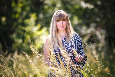 Güzel kız ormanın çalılıklarında duruyor.