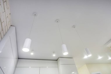 Halojen lambalı asma tavan ve boş bir oda ya da evde alçıpan inşaatı. Gergin tavan beyaz ve karmaşık şekil.