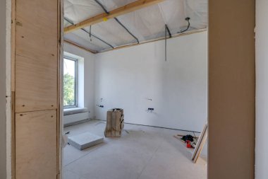 Minimum hazırlık onarımı yapılmış mobilyasız bir oda. Beyaz duvarlar ve alçıpanla iç mekan