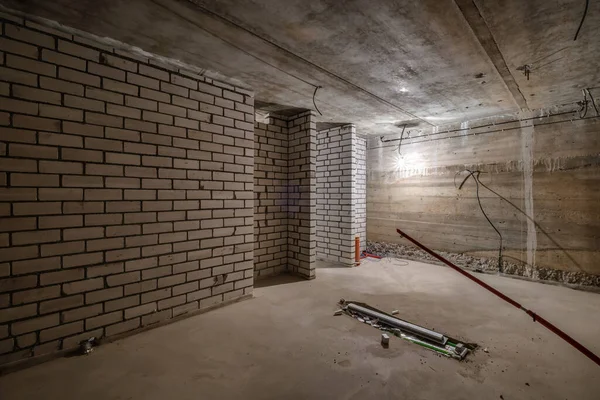 Mobilyasız bodrum odası ve minimum hazırlık onarımı. Beyaz tuğlalı duvarlarla iç içe