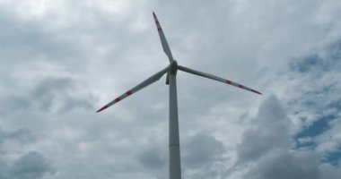 Mavi gökyüzü arka planında bulutlu bir yel değirmeni pervanesinin dönen pervaneleri. Rüzgar enerjisi üretimi. Saf yeşil enerji.