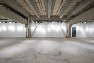 Büyük beton odanın içi depo ya da spot ışıkları olan bir hangar gibi boş.