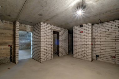 Minimum hazırlık onarımı olan boş bir bodrum odası. Beyaz tuğlalı duvarlarla iç içe