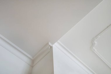 Köşedeki tavan ve duvarların ayrıntıları. Karmaşık taç kalıplarıyla. İç yapı ve yenileme konsepti.