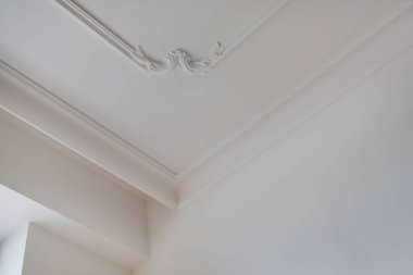 Tavan ve duvarların köşesinde karmaşık taç kalıpları var. İç yapı ve yenileme konsepti.