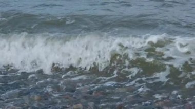 Deniz dalgaları ağır çekimde güçlü bir şekilde kıyıya çarpar.