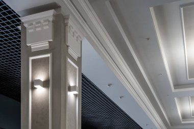 İçerideki sütunlarda halojen benekli lambalar ve boş oda ya da evdeki alçıpan inşaatı ile birlikte asılmış ve ızgara tavanı var. Gergin tavan beyaz ve karmaşık şekil.