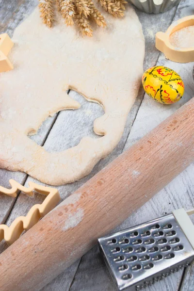 Preparazione di cottura pasquale. Pasta cruda e forma per i biscotti di festa su un tavolo di legno . — Foto Stock