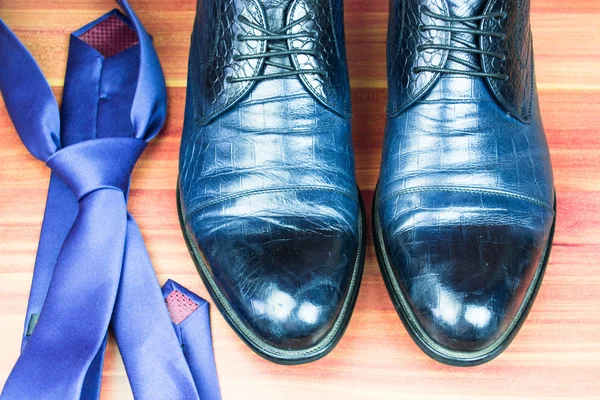 Классические мужские туфли и синий галстук на деревянном фоне — стоковое фото