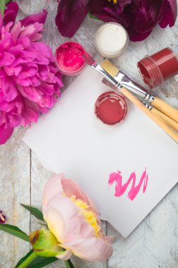 Çalışma alanı. Beyaz arka plan üzerinde izole suluboya, fırça ve pembe peonies. Havai görünümü. Düz yatıyordu, en iyi görünümü