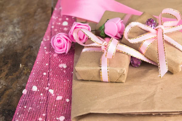 Δώρο πλαίσιο διακόσμηση. Τυλιγμένο σε χαρτί περγαμηνή, λεπτή φρέσκα ροζ λουλούδια με χρυσή καρδιά — Φωτογραφία Αρχείου