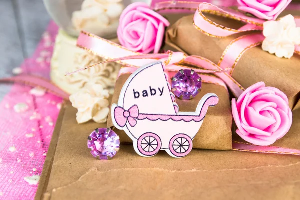 Pink wooden carriage figure with wrapped presents. Girl birth concept