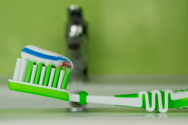 Green toothbrush on a green background — Stock Photo, Image