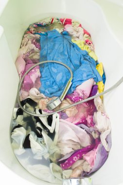 Dirty clothes soak in tub with detergent before washing clipart
